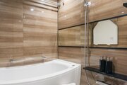 横長ミラーの効果で実際のサイズよりも広がりを感じるバスルームです。光沢感のある木目調のパネルが、より一層くつろぎと高級感を醸し出します。