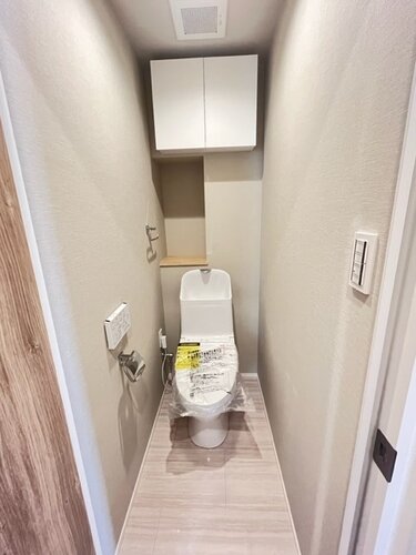 トイレ ・ウォシュレット一体型のトイレは、お掃除の手助けをしてくれる便利機能が搭載されています。上部には吊戸棚を造作しました。トイレットペーパーや掃除用品なども収納できます。 トイレ ・ウォシュレット一体型のトイレは、お掃除の手助けをしてくれる便利機能が搭載されています。上部には吊戸棚を造作しました。トイレットペーパーや掃除用品なども収納できます。