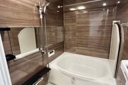 浴室　・横長ミラーの効果で実際のサイズよりも広がりを感じるバスルームです。光沢感のある木目調のパネルが、より一層くつろぎと高級感を醸し出します。