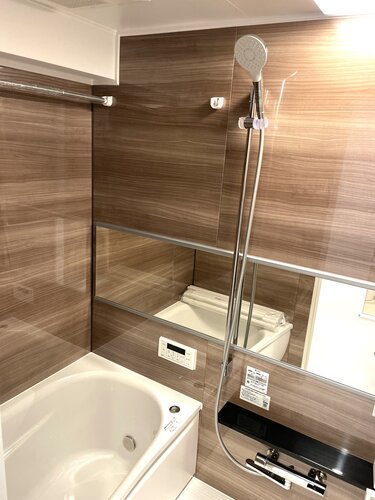 浴室　・木目調のアクセントパネルがよりくつろぎの空間を醸し出します。美しいカーブと全身を包み込むような入浴感が特長のクレイドル浴槽を採用しました。
