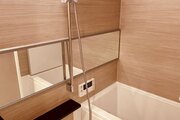 浴室　・横長ミラーの効果で実際のサイズよりも広がりを感じるバスルームです。光沢感のある木目調のパネルが、より一層くつろぎと高級感を醸し出します。