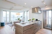 上質なお部屋に溶け込む、木目調デザインの田中工藝製オープンキッチンです。キッチン横手の扉はバルコニーへとつながっているため、採光性や換気面も良好ですね。