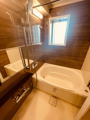 浴室　・光沢感のある木目調のパネルが、より一層くつろぎと高級感を醸し出します。また、窓もあり明るく快適なバスタイムをお楽しみいただけます。